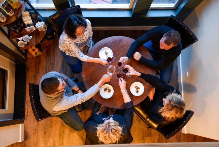 5 guests toasting with wine glasses at table in lobby